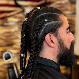 Tresses plaquées et anneaux sur cheveux longs, barbe travaillée — La Barbière